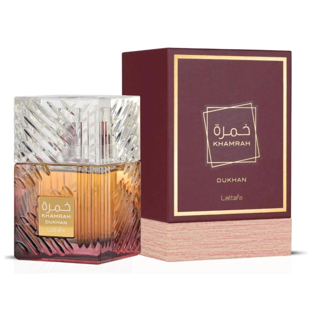 Frasco de cristal tallado con perfume ámbar y base burdeos, junto a su caja burdeos y dorada, de Khamrah Dukhan Eau de Parfum de Lattafa, 100 ml.